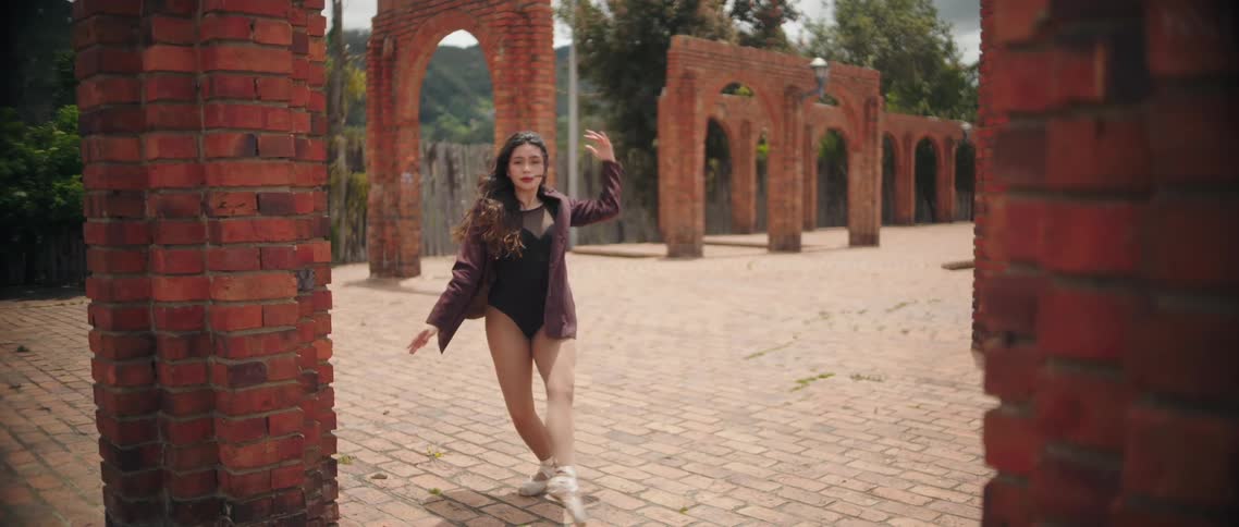 Female ballet dancer dances in a plaza decorated with brick arches