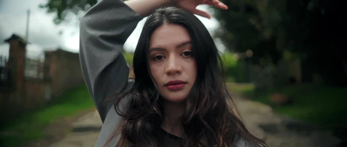 Woman positions her hands around her face while holding a gentle expression