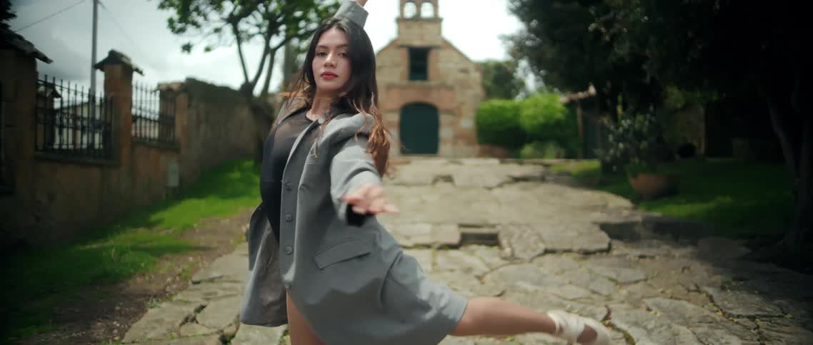Dancer holds a balanced pose on a stone pathway with arms extended