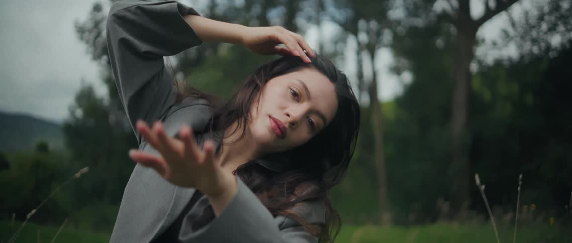 Woman moves through multiple poses while standing in a rural field