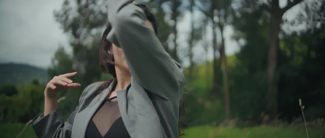 Woman moves her arms gently while performing a soft pose in the field