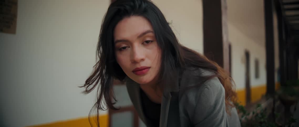 Woman in a blazer maintains a direct and gentle gaze