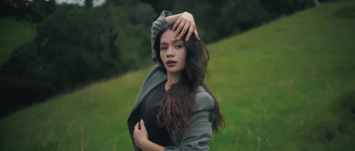 Woman standing on a grass covered hill moving her arms in a dancing motion