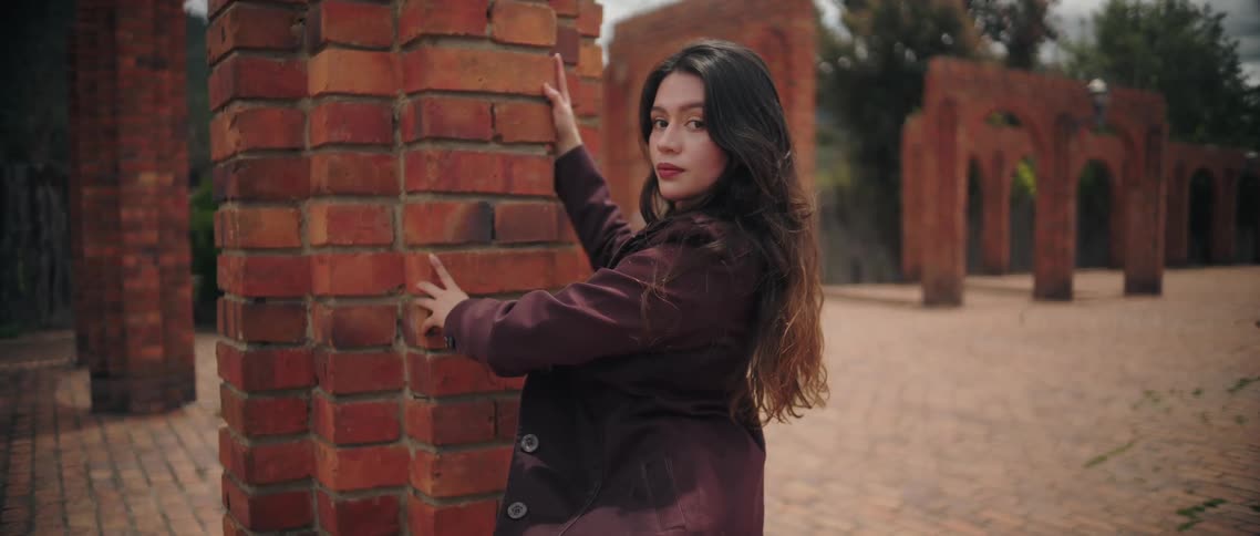 A woman standing outdoors near a brick wall