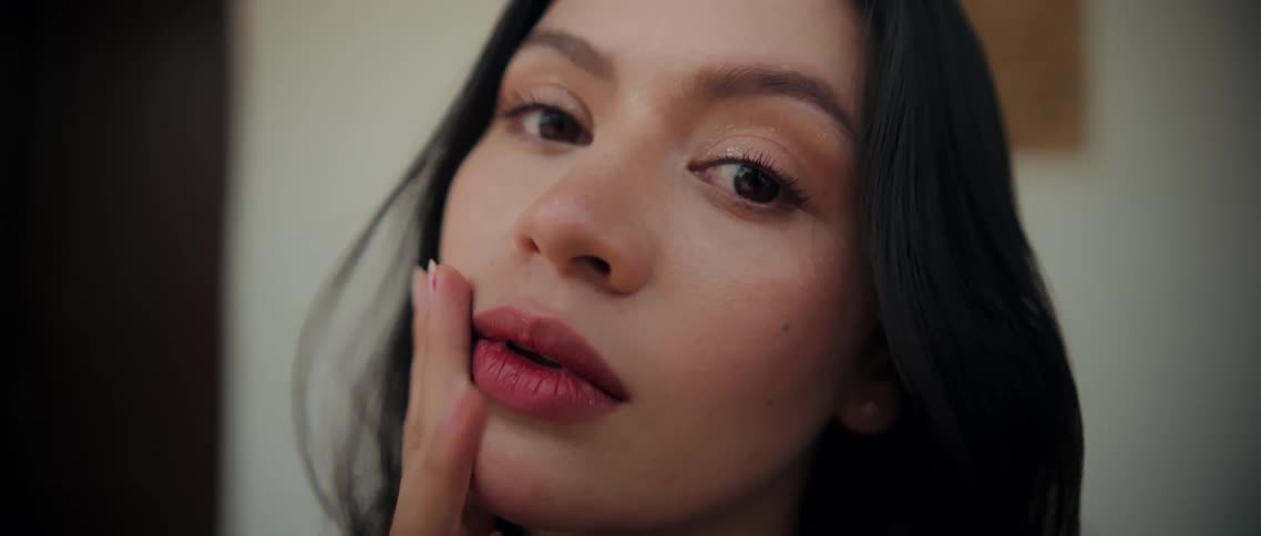 Woman touches her face with her fingertips while holding a soft