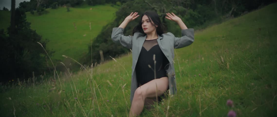 Woman on a grass covered hill practicing tai chi