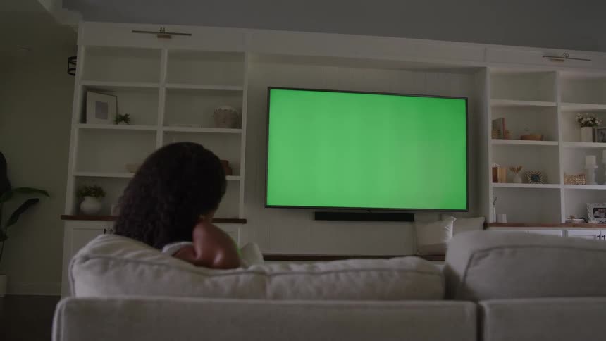 A woman sitting on a couch watching tv