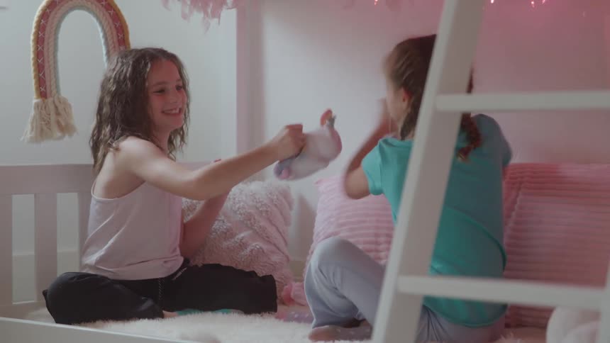 Two girls playing with plush toys on the bed