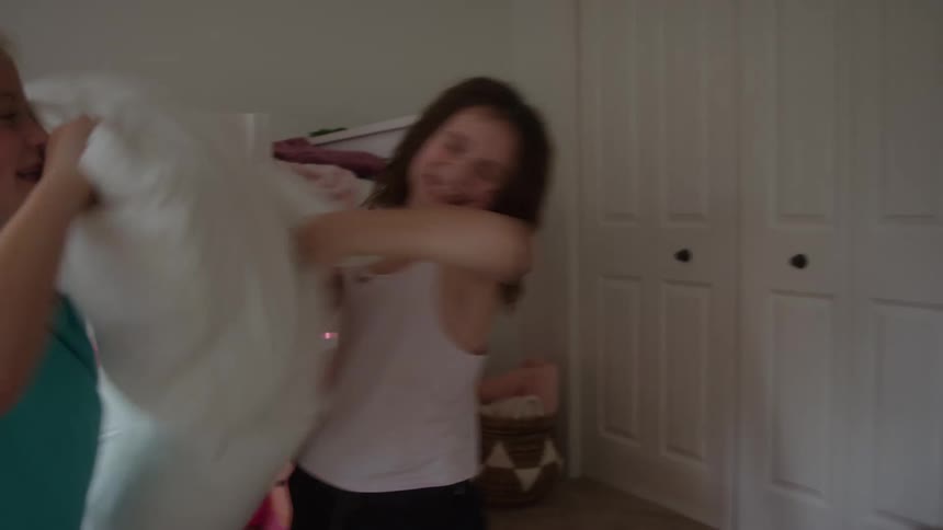 Two girls have a pillow fight in the bedroom