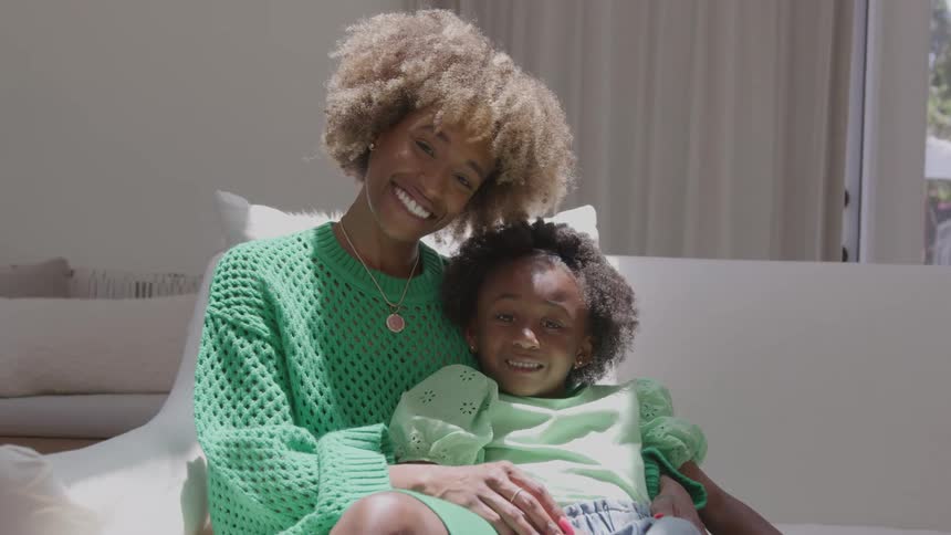 Mother hugging her smiling daughter in a bright setting