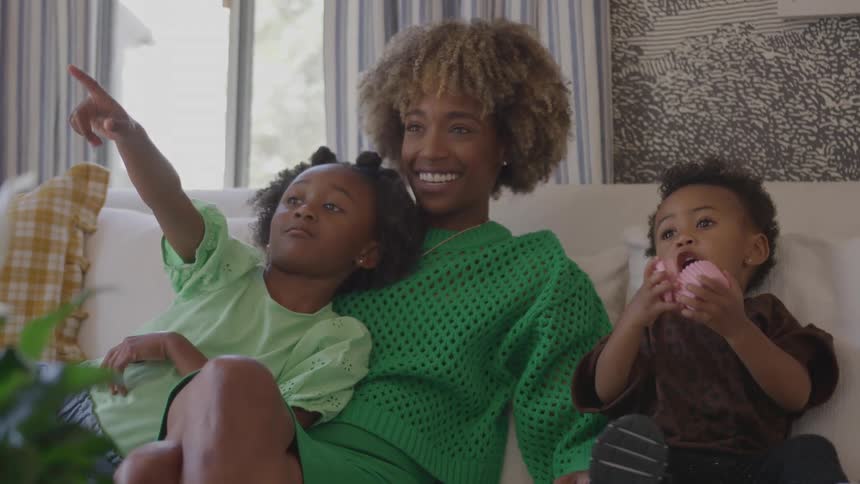Children sitting with their mother while pointing and playing on the couch