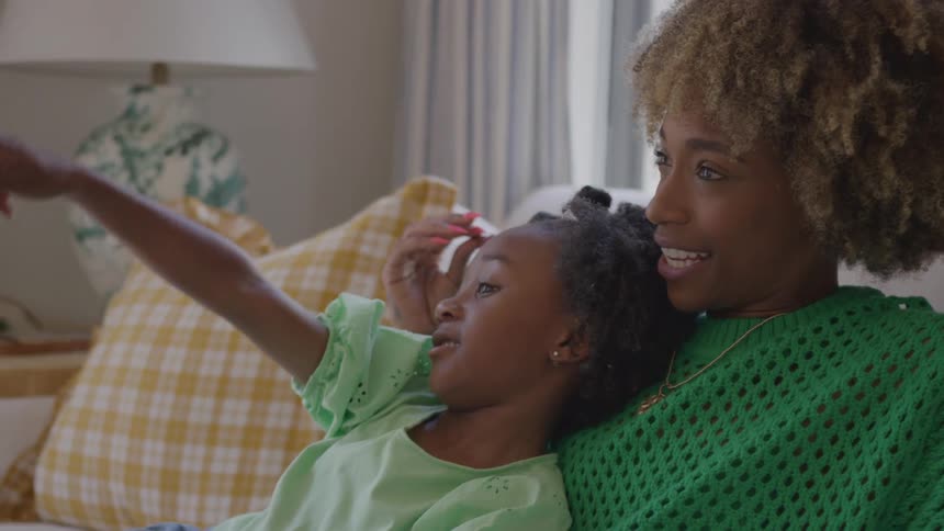 Mother lying on the couch hugging her daughter as they talk