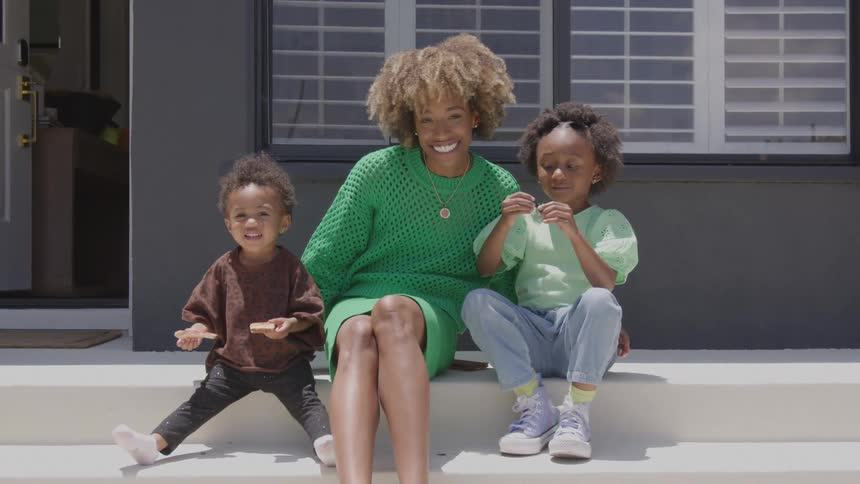 Mother and her children sitting on the steps smile
