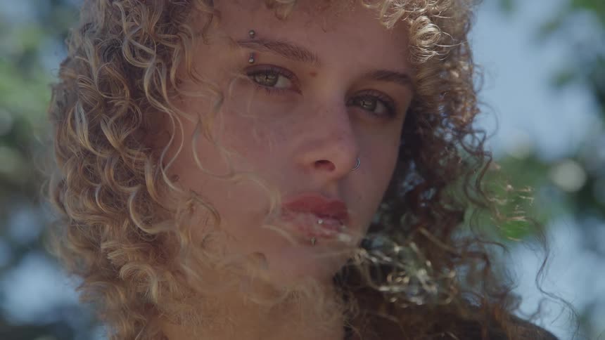 Young woman looking directly with a serious expression in natural light