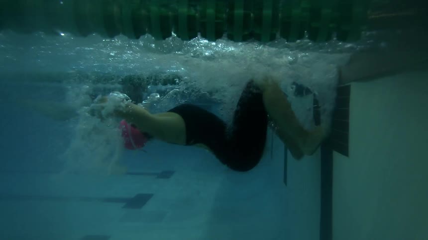 A woman turns around swimming in a pool