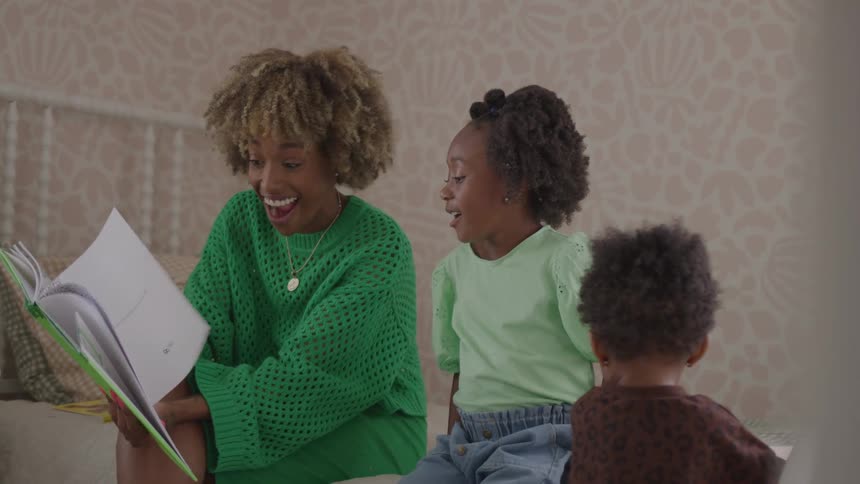 Mother reading a book to her children at home
