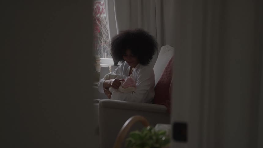 The mother is holding her daughter by the window