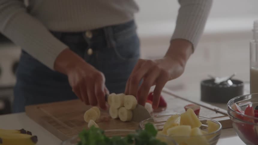 Woman standing at the kitchen counter slicing a banana