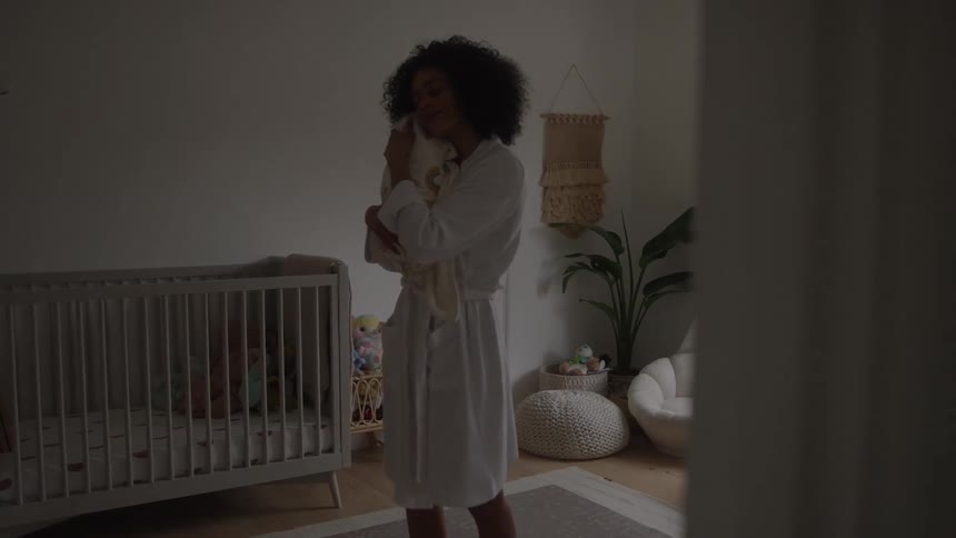 Woman stands in the bedroom comforting her baby in her arms