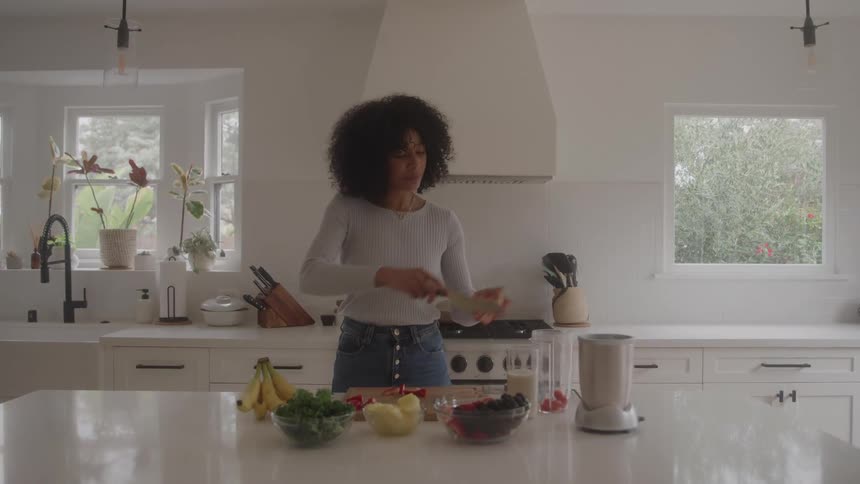Woman standing at the kitchen counter slicing vegetables on a cutting board