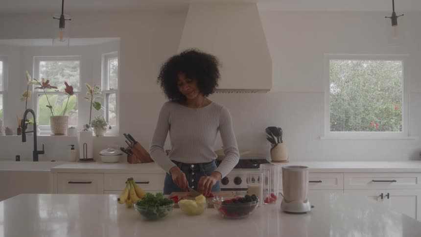 Woman standing at the kitchen counter slicing vegetables on a cutting board