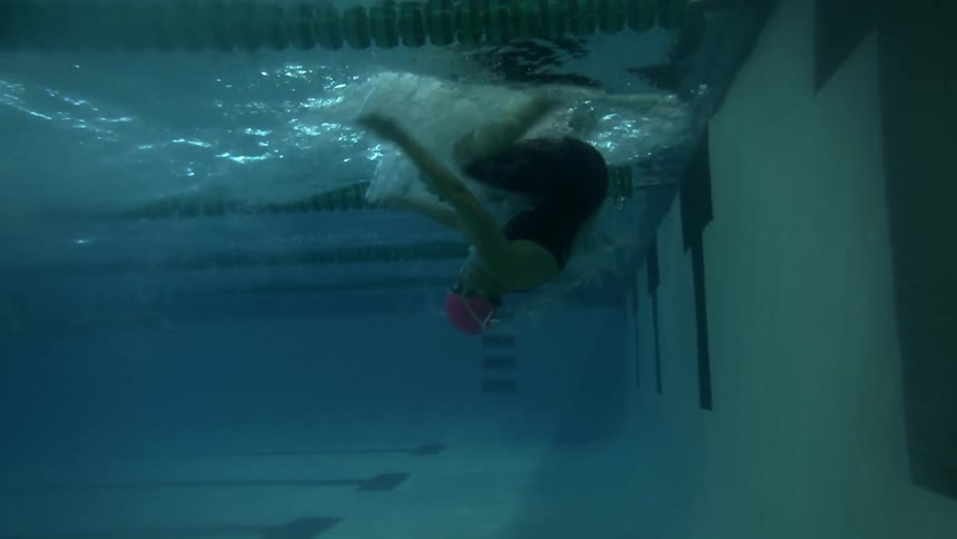 A person swimming underwater in a pool