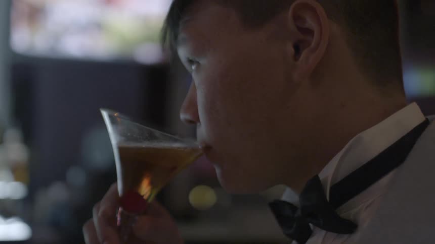 Man sits at a bar and takes a drink out of a martini glass