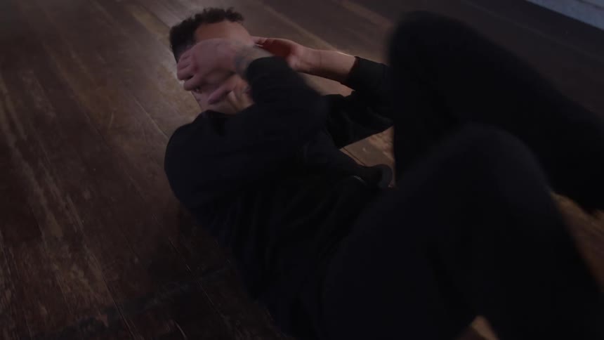 Man lying on a wooden floor performing a crunch