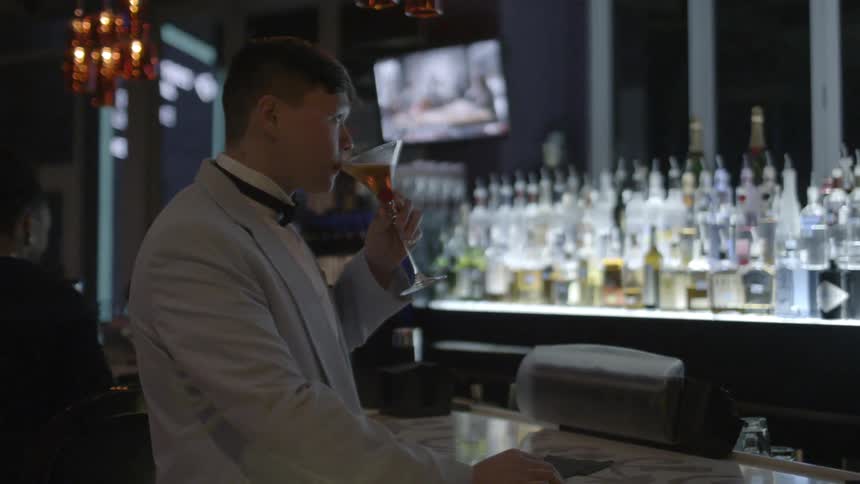 Man wearing a suit drinks at a bar