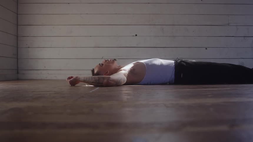 Man lying on the wooden floor breathes heavily after intense exertion