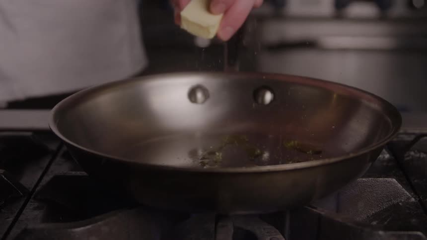 Male chef preps a skillet by adding oil and butter