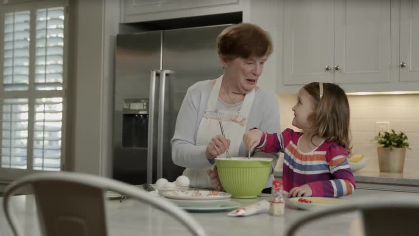 A woman and child mix a bowl and talk