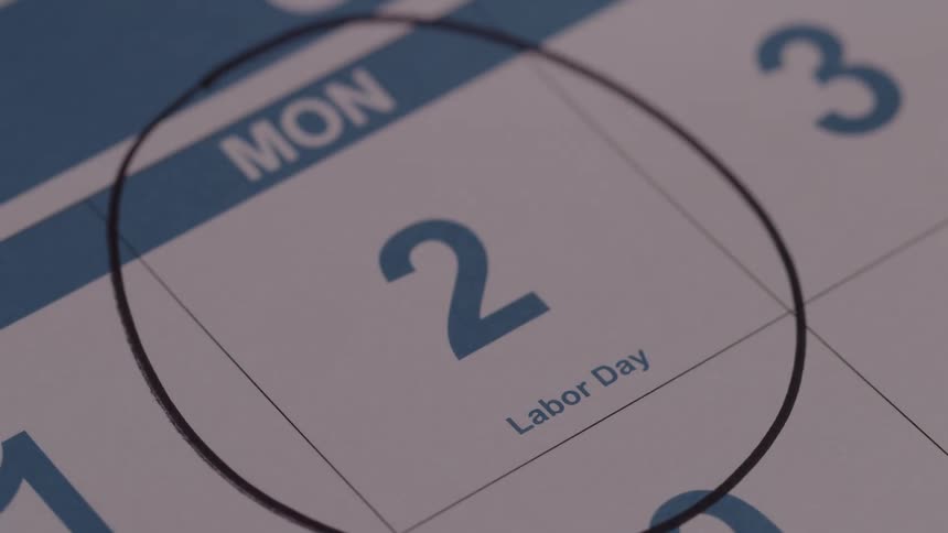Close up of a person circling a date on a calendar with a black marker