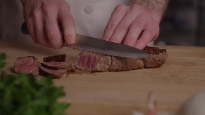Cook slicing a juicy steak on the cutting board