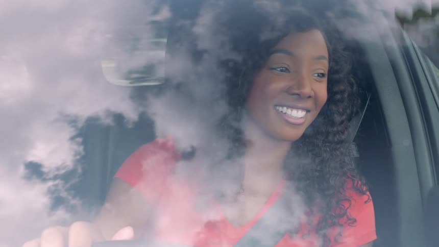 Woman smiling inside the car seen through the reflection of clouds on the window