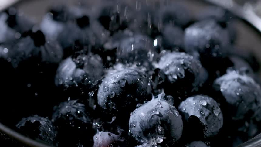 Blueberries being rinsed as water runs over their dark skins
