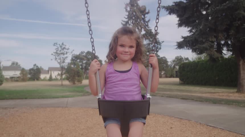 Girl swinging at the playground on a sunny day