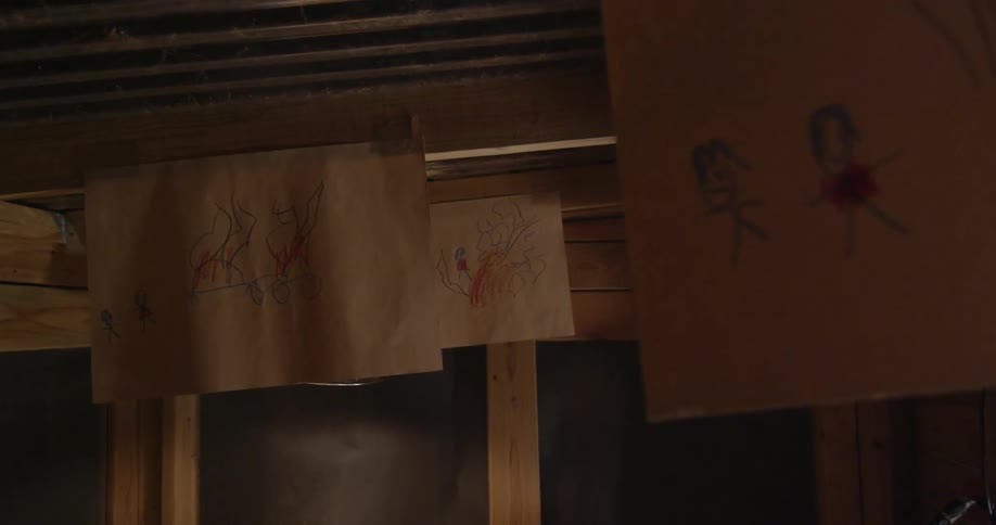 Children's drawings are taped to the ceiling beams
