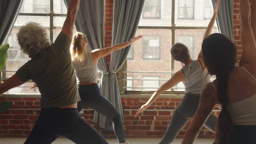 Group of women standing in a room stretching out their arms and exercising