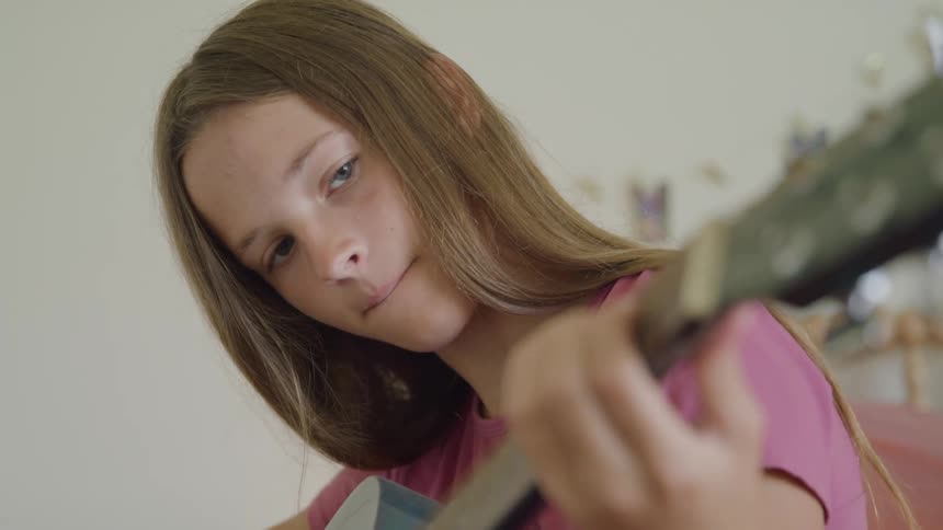 Girl focused while playing the guitar in her room