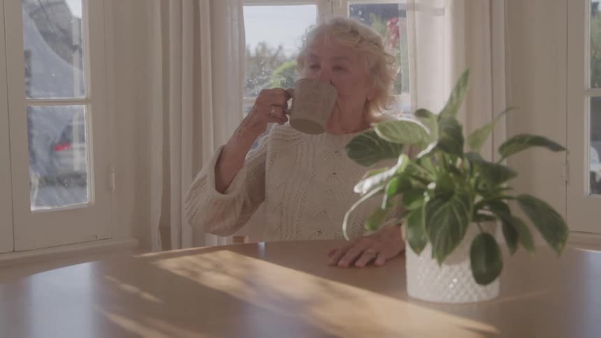 Woman sitting at a table drinking a cup of coffee