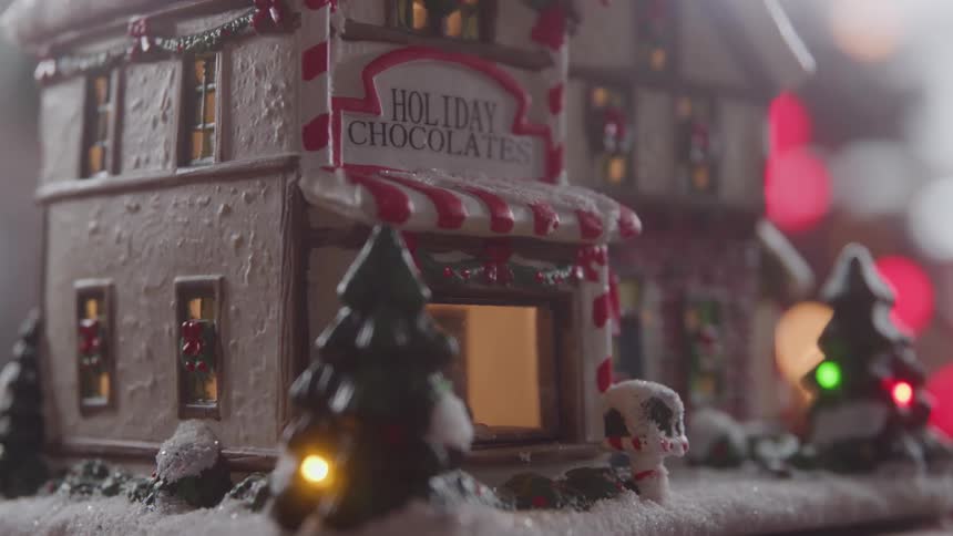 Miniature holiday chocolate shop glowing among snowy decorations