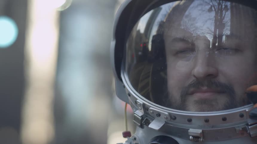 A man wears an astronaut suit and closes the helmet