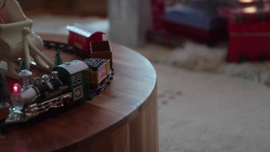Toy train with lights running around a christmasthemed table