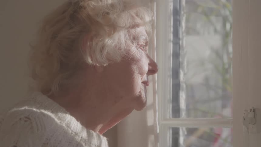 Elderly woman watching the light come through the window