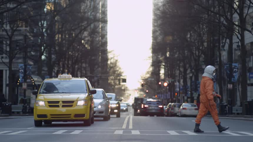 A person wearing a space helmet walking across a street