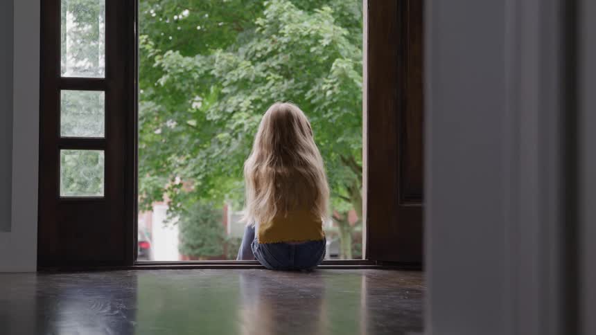 The child is sitting in the doorway of the home