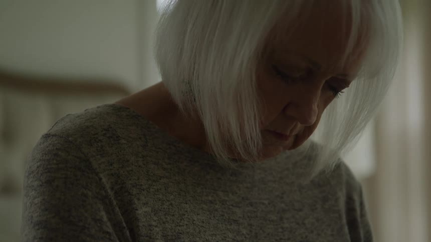 Elderly person with white hair in a softly lit residential setting