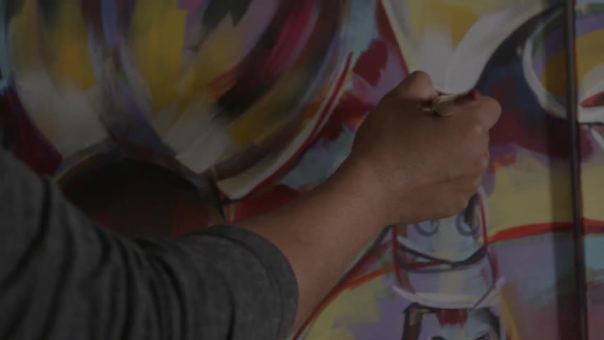 A man paints on a large canvas with a brush