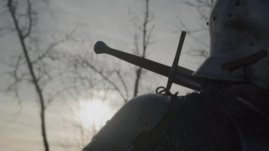Person in medieval armor walks outdoors at sunset